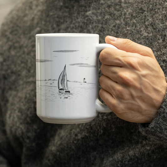 Close-up of a model holding a 15oz ceramic mug featuring a hand-drawn sailboat and lighthouse ocean scene in a minimalist pen-and-ink illustration, perfect for nautical and coastal theme lovers.