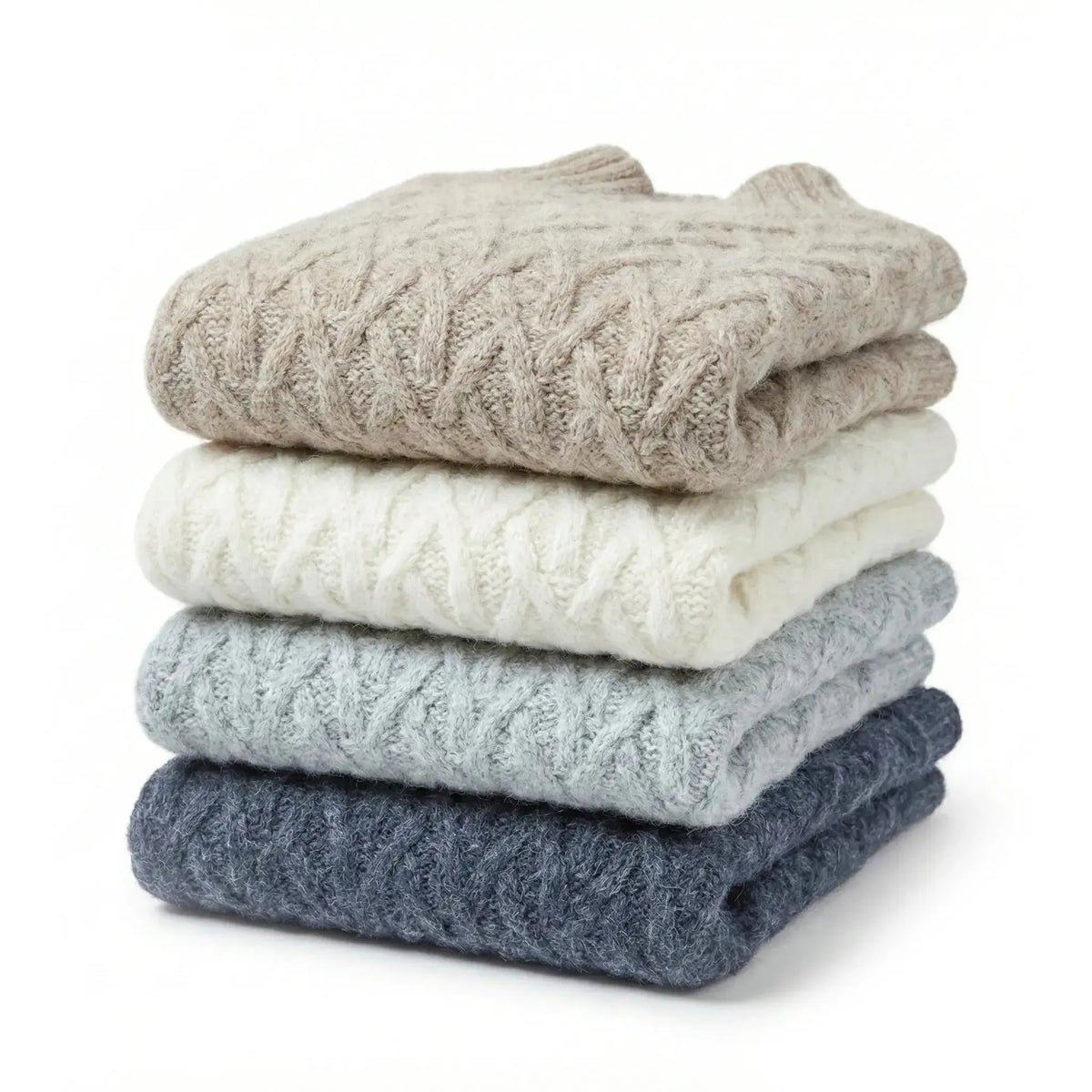 Stack of folded cable knit sweaters in beige, white, gray, and navy on a white background