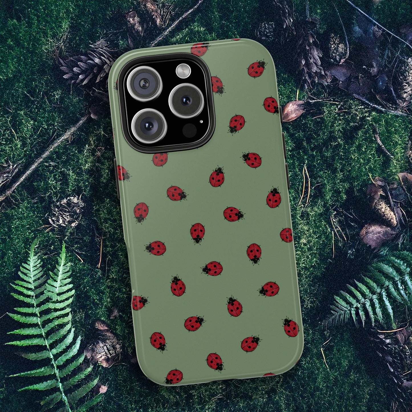 Phone case with ladybug pattern on a green forest floor background.