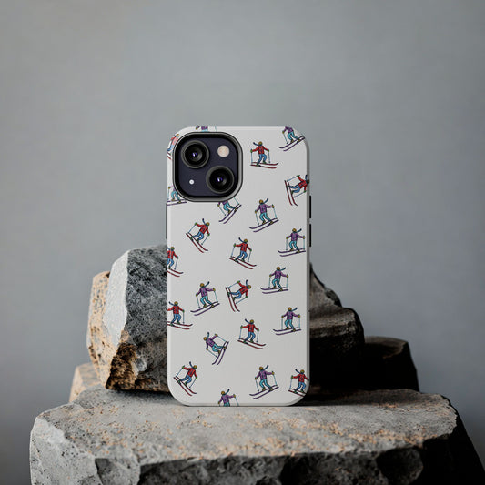 Lifestyle shot of a cell phone case with illustrated skiers resting on rugged rocks, highlighting its outdoor-inspired skiing pattern and durable design.