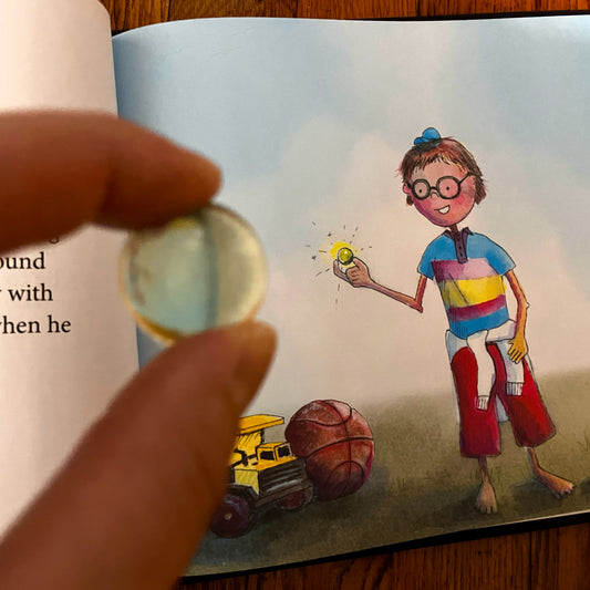 Illustration of a child with a light bulb, toy truck, and ball on a book page.