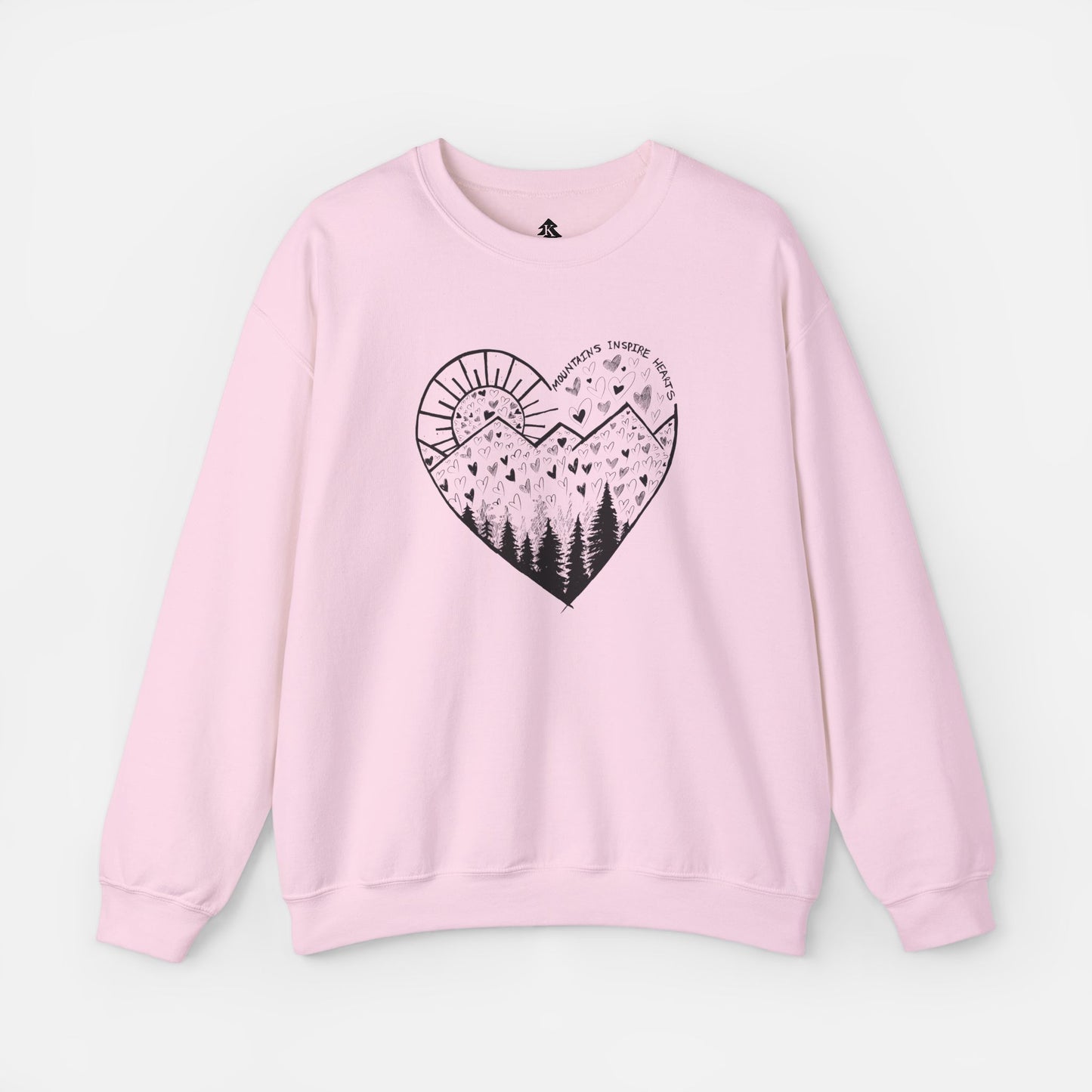A light pink crewneck sweatshirt featuring a heart-shaped mountain design with the text and Mountains Inspire Hearts, perfect for anyone that loves hiking, mountain views, or the outdoors.