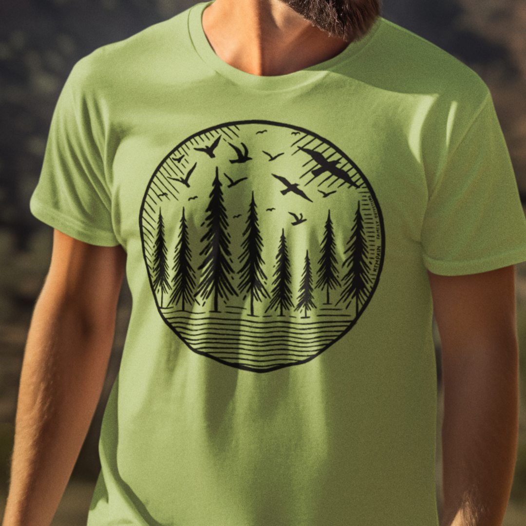 Model wearing Wildwood Flight T-Shirt, featuring a hand-drawn geometric design of soaring birds and towering pine trees, perfect for nature lovers and outdoor explorers.