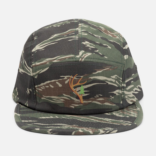 Front view of the Antler & Pine embroidered 5-panel camo hat on a white background, featuring a unique antler turning into a pine tree design centered on the panel.