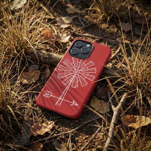 Red phone case with illustrated weather vane design on a ground covered with dry grass and leaves