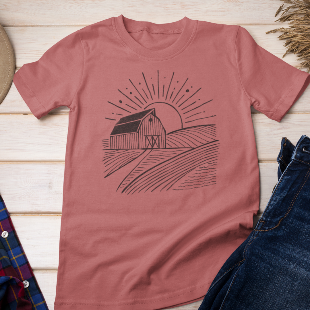 Coral color Farm Barn Scene T-Shirt laid out on a rustic wood floor with jeans, a cowgirl hat, and boots, creating a stylish country-inspired outfit for farmers and country living enthusiasts.