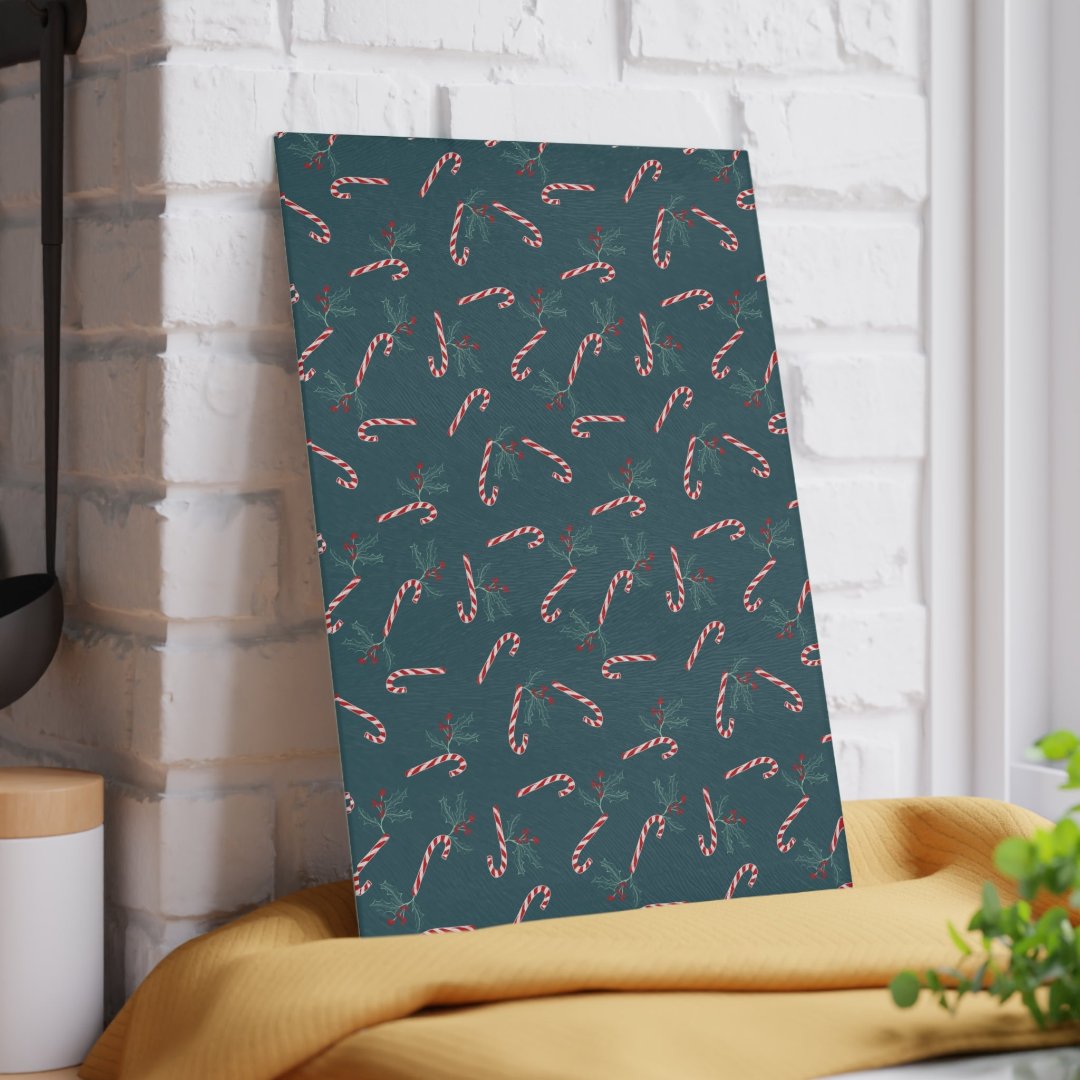 Glass cutting board featuring a candy cane and holly pattern, leaned against a wall in a kitchen setting, adding a festive touch to holiday decor.