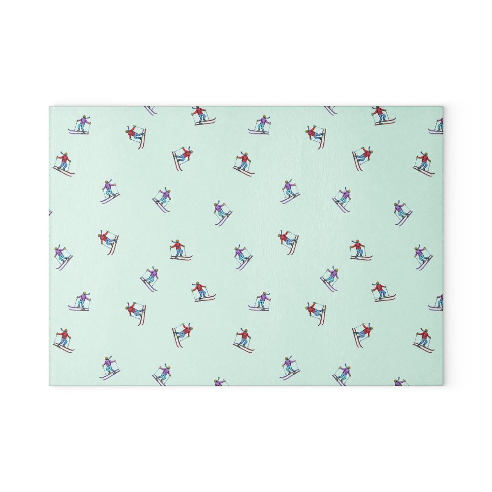 Glass cutting board featuring an illustrated skier pattern, titled 'Carving the Slopes,' displayed on a white background, perfect for winter sports enthusiasts and holiday kitchens.