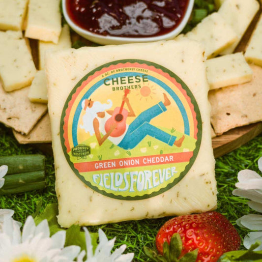 Green Onion Cheddar by Cheese Brothers, Inc. sold by Kempain Family Outfitters displayed in near a cheese board with crackers and jam.