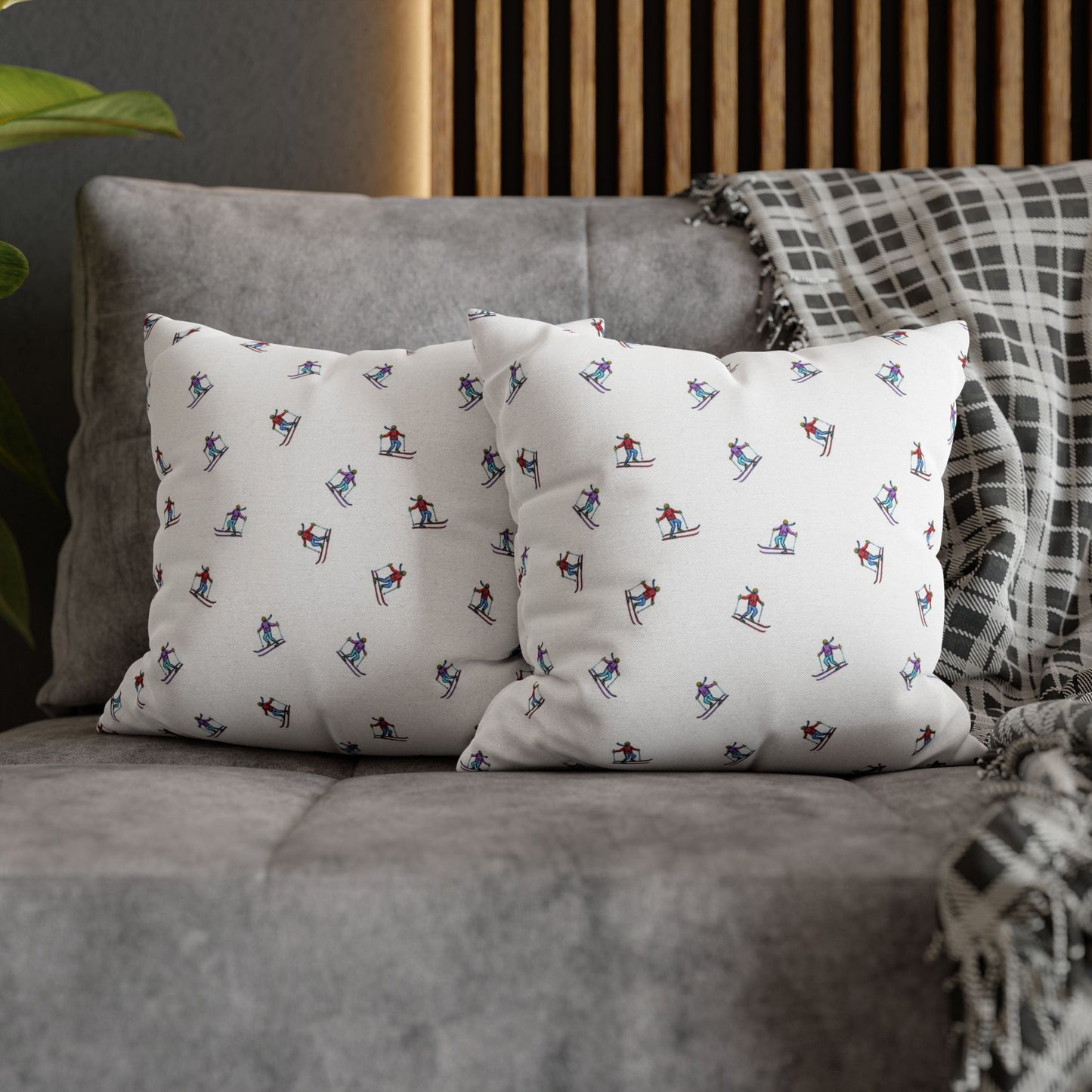 Lifestyle view of two pillow cases with an illustrated skier pattern, titled 'Carving the Slopes,' placed on a couch, bringing a winter sports-inspired touch to the living room decor.