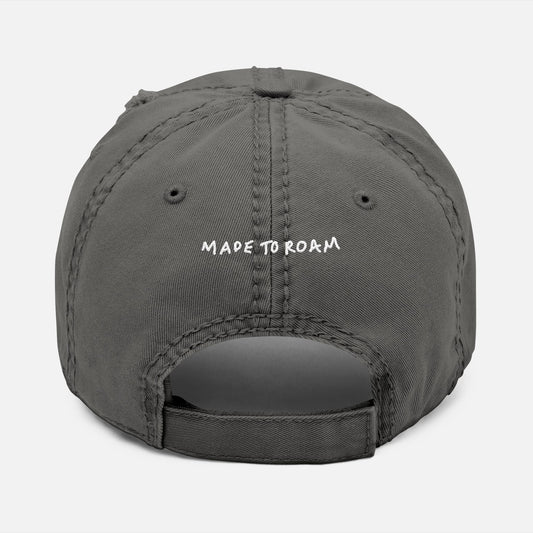 Back view of grey distressed dad hat on white background with “Made to Roam” embroidered in hand-drawn script.