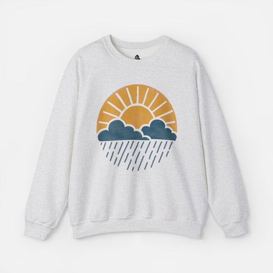 Flat lay of Sun Over Clouds Minimalist Sweatshirt in grey fabric on a white background, featuring a simple line art illustration of a sunrise over clouds and rain within a subtle circle, printed on a classic unisex crewneck.