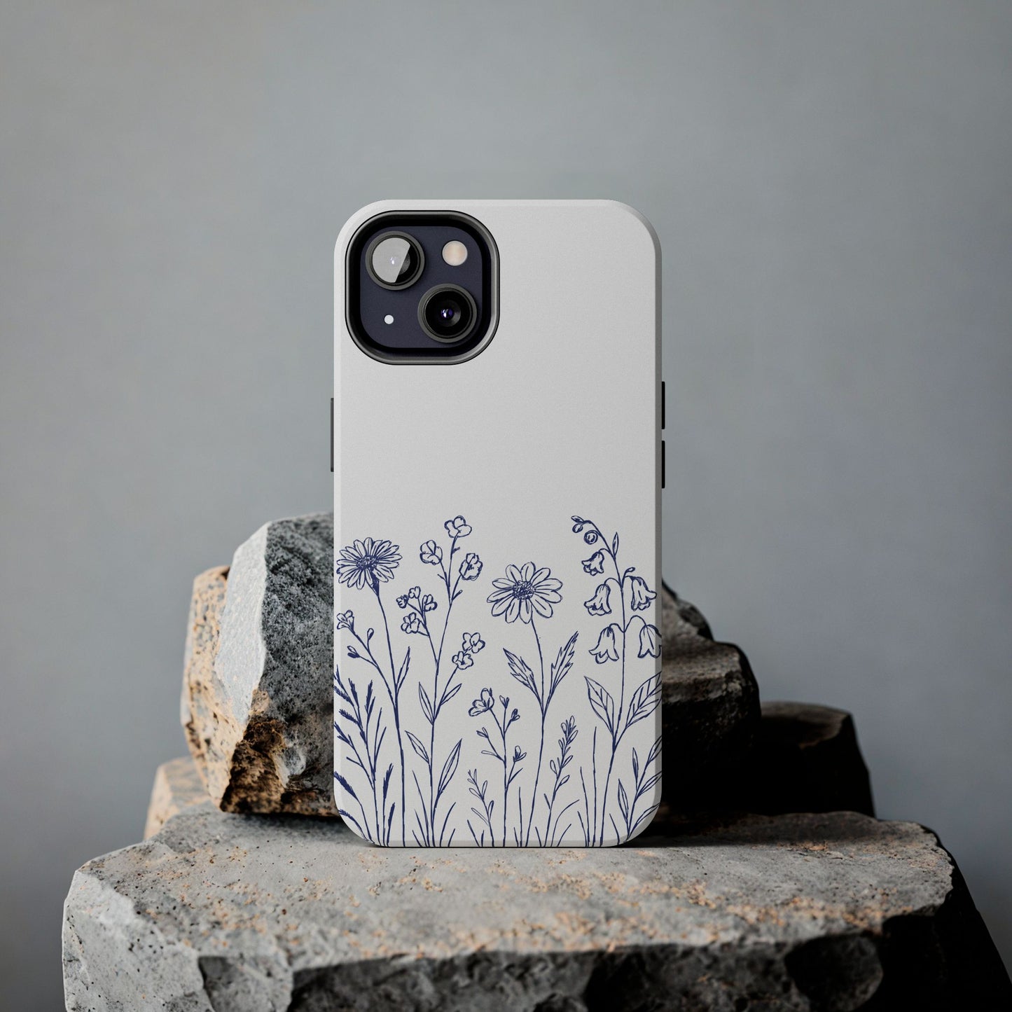 Wildflower Blue Phone Case featuring delicate hand-drawn floral design in serene blue on a rock.