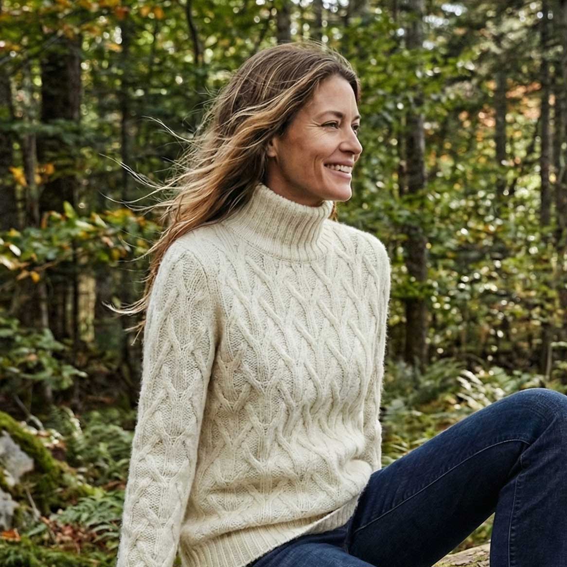 Woman wearing a cream sweater sitting in a forest