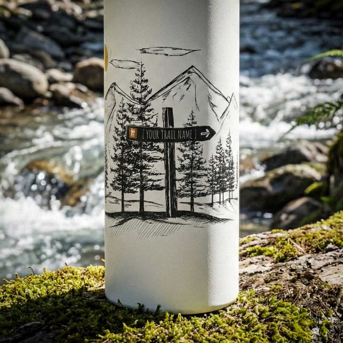 A 12oz water bottle placed on a mountain rock in snowy winter setting featuring a custom blue trail ski marker illustration with custom text placeholder for you to personalize. 