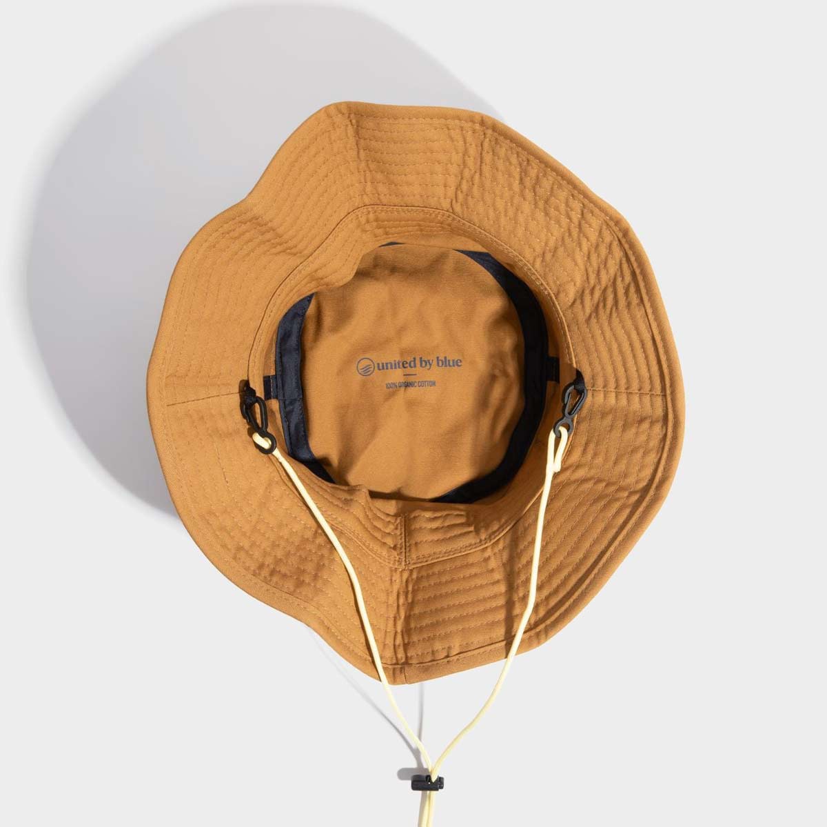 100% Organic Cotton Utility Bucket Hat by United By Blue displayed on white background detailing the inside of the hat and logo "United by Blue".