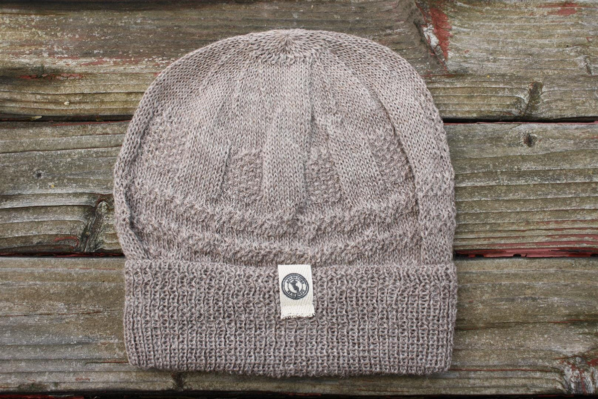 Light brown 100 percent baby alpaca knit winter hat by Purely Alpaca on wooden surface.