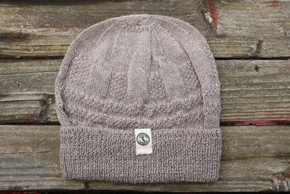 Light brown 100 percent baby alpaca knit winter hat by Purely Alpaca on wooden surface.