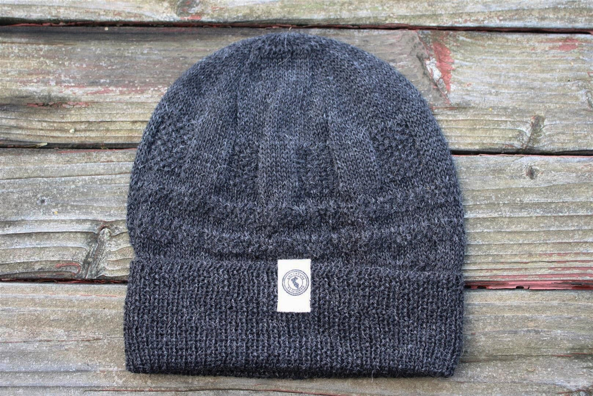 100 percent baby alpaca knit winter hat by Purely Alpaca in Charcoal color option displayed on a wooden surface.