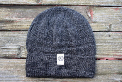 100 percent baby alpaca knit winter hat by Purely Alpaca in Charcoal color option displayed on a wooden surface.