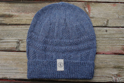 100 percent baby alpaca knit winter hat by Purely Alpaca in Denim color option displayed on a wooden surface.
