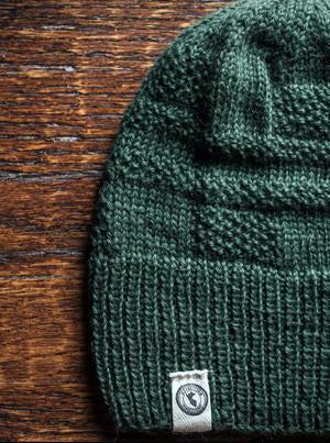 100 percent baby alpaca knit winter hat by Purely Alpaca in Green color option on a wooden surface.