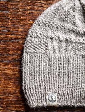 100 percent baby alpaca knit winter hat by Purely Alpaca in Oatmeal color option on a wooden surface.