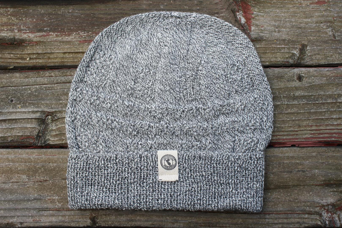 100 percent baby alpaca knit winter hat by Purely Alpaca in Salt and Pepper color option displayed on a wooden surface.