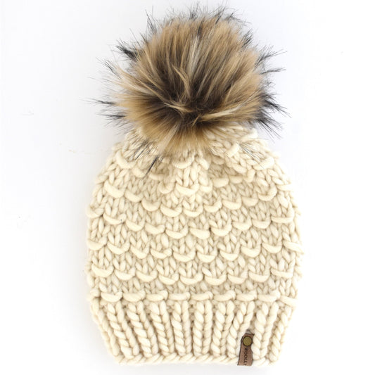 Beige knitted beanie with a fur pom-pom on a white background