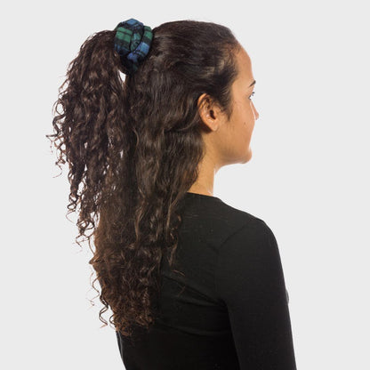 Woman with curly hair tied back with a plaid Vermont Flannel Company scrunchie on a white background.