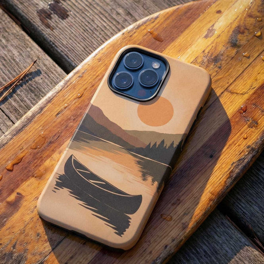 Canoe on Still Lake Phone Case featuring a peaceful lake scene with a canoe and forest reflection, shown on a rustic paddle and dock. 