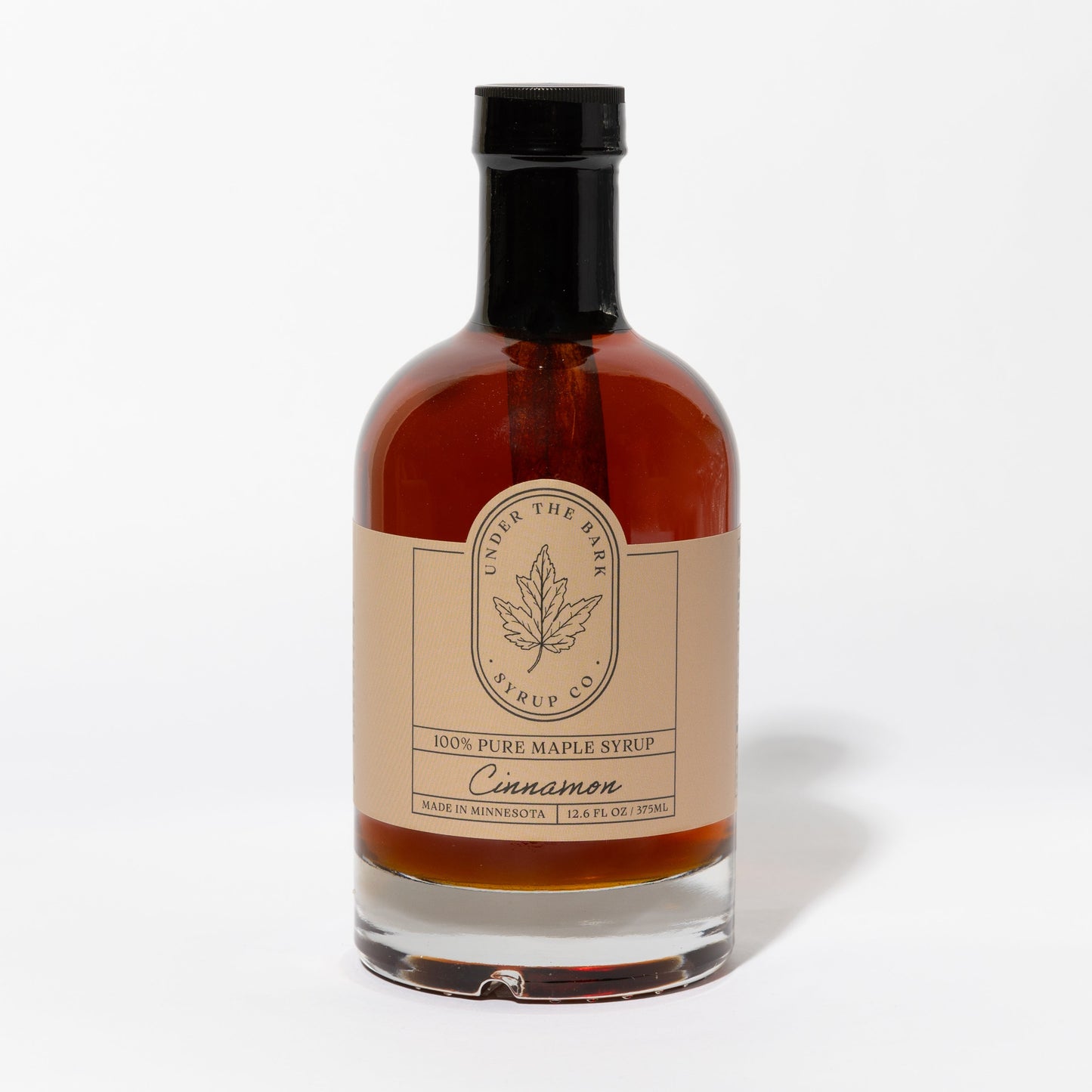 12.6 FL OZ Bottle of cinnamon-flavored 100% pure maple syrup by Under The Bark Syrup Co. on a white background.