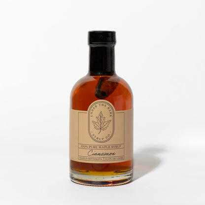 8.4 FL OZ Bottle of cinnamon-flavored 100% pure maple syrup by Under The Bark Syrup Co. on a white background.