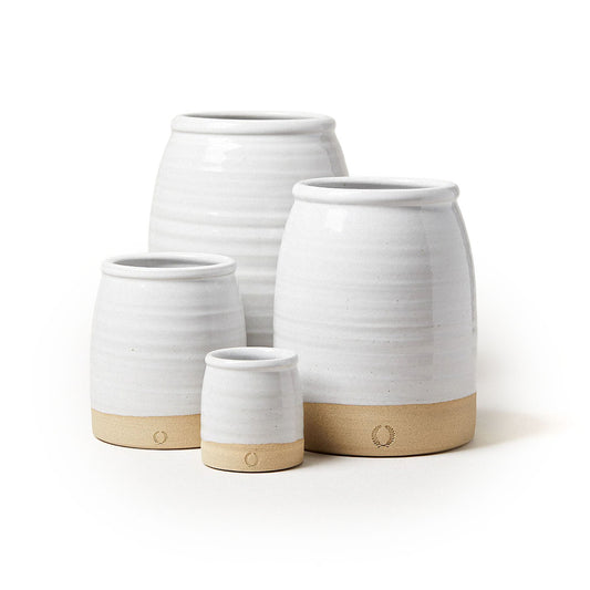 Four white ceramic pots with wooden bases on a white background