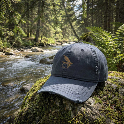 Blue cap with a fly design on a mossy rock by a forest stream
