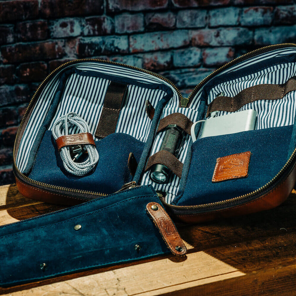 Full-Grain Leather Electronics / Toiletry Organizer displayed on a open with electronics in a rustic setting.