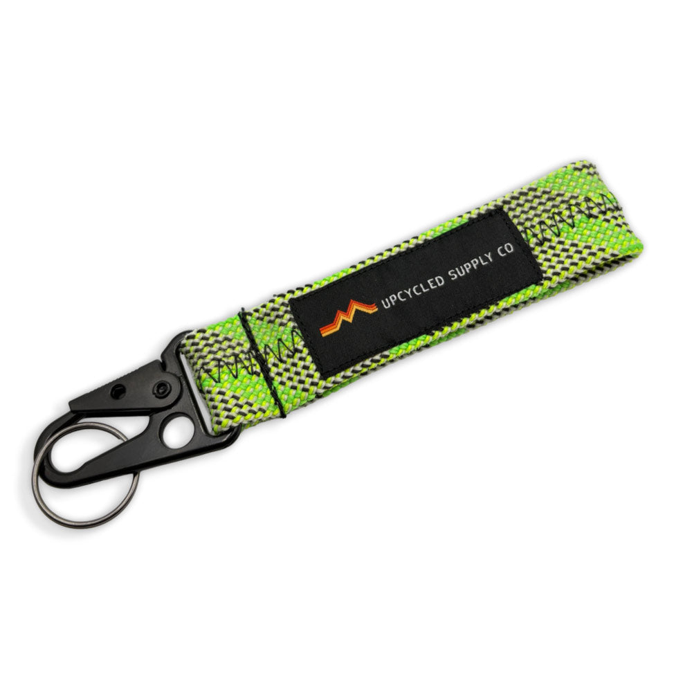 A green braided climbing rope recycled fabric keychain with a black metal carabiner and a black label reading 'UPCYLED SUPPLY CO' on a white background.