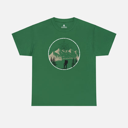 A green Unisex Cotton Tee on white background, featuring a captivating hand-drawn illustration that encapsulates the spirit of hiking. Featuring majestic mountains and a compass rising in the sky that beckons the call of adventure. 