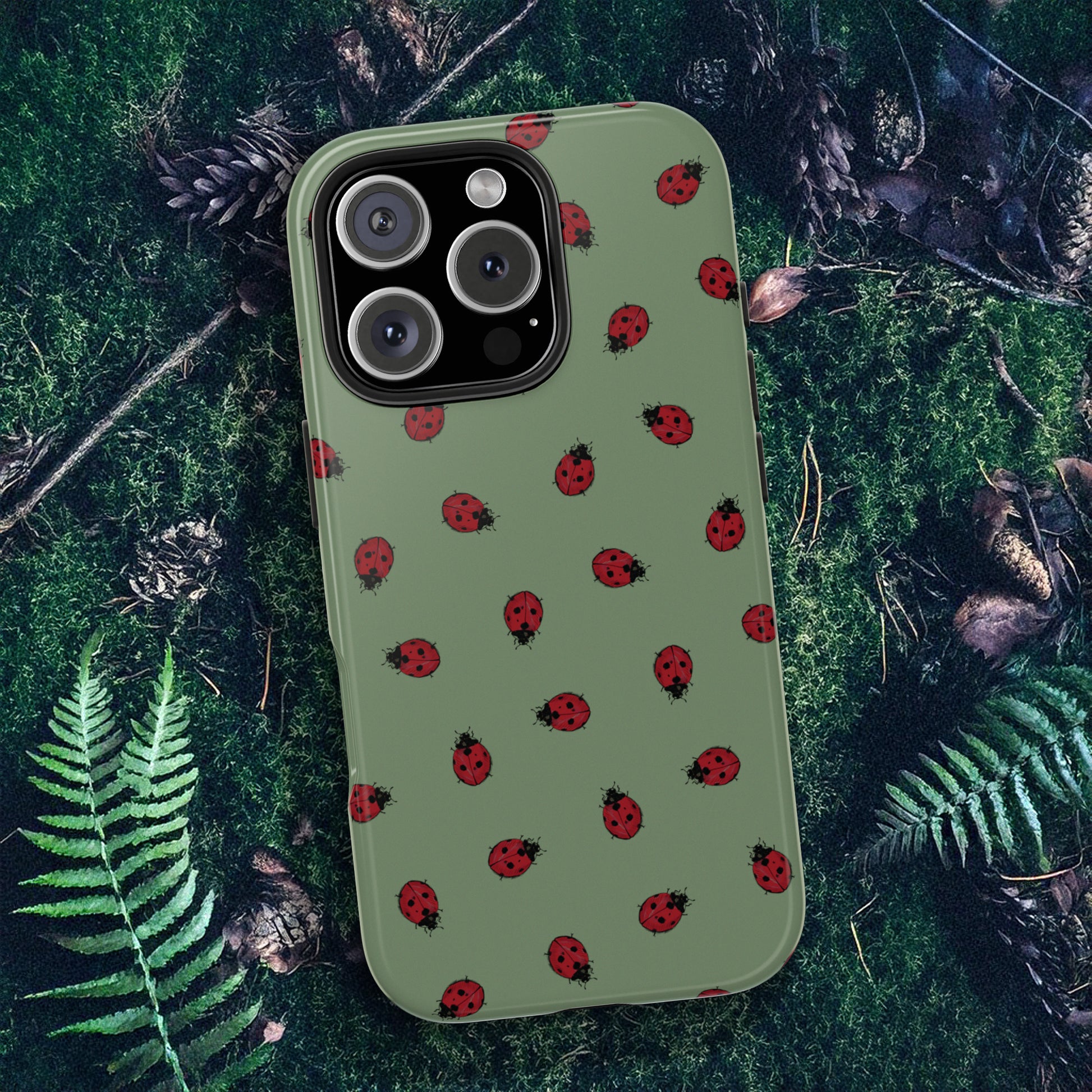 Phone case with ladybug pattern on a green forest floor background.