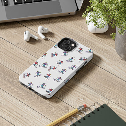 Lifestyle image of a cell phone case with illustrated skiers, lying flat on a desk, showcasing its vibrant mountain-inspired skiing pattern.