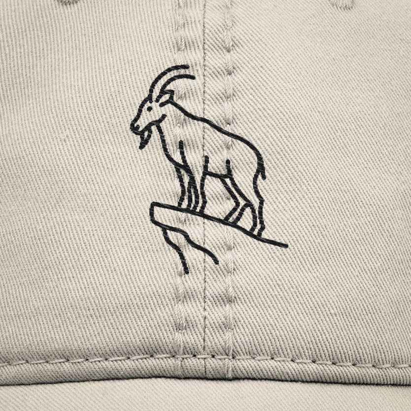 Close up of beige dad hat with black goat illustration embroidered on a beige cotton.
