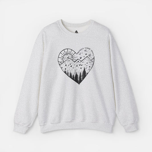 A light gray crewneck sweatshirt featuring a heart-shaped mountain design with the text and Mountains Inspire Hearts, perfect for anyone that loves hiking, mountain views, or the outdoors.
