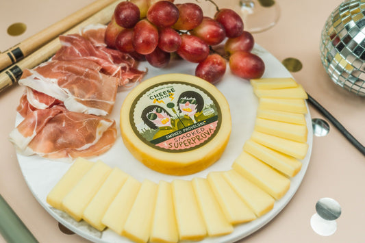 Platter of cheese, prosciutto, and grapes showcasing the Cheese Brothers Wisconsin  Artisan Cheese. 