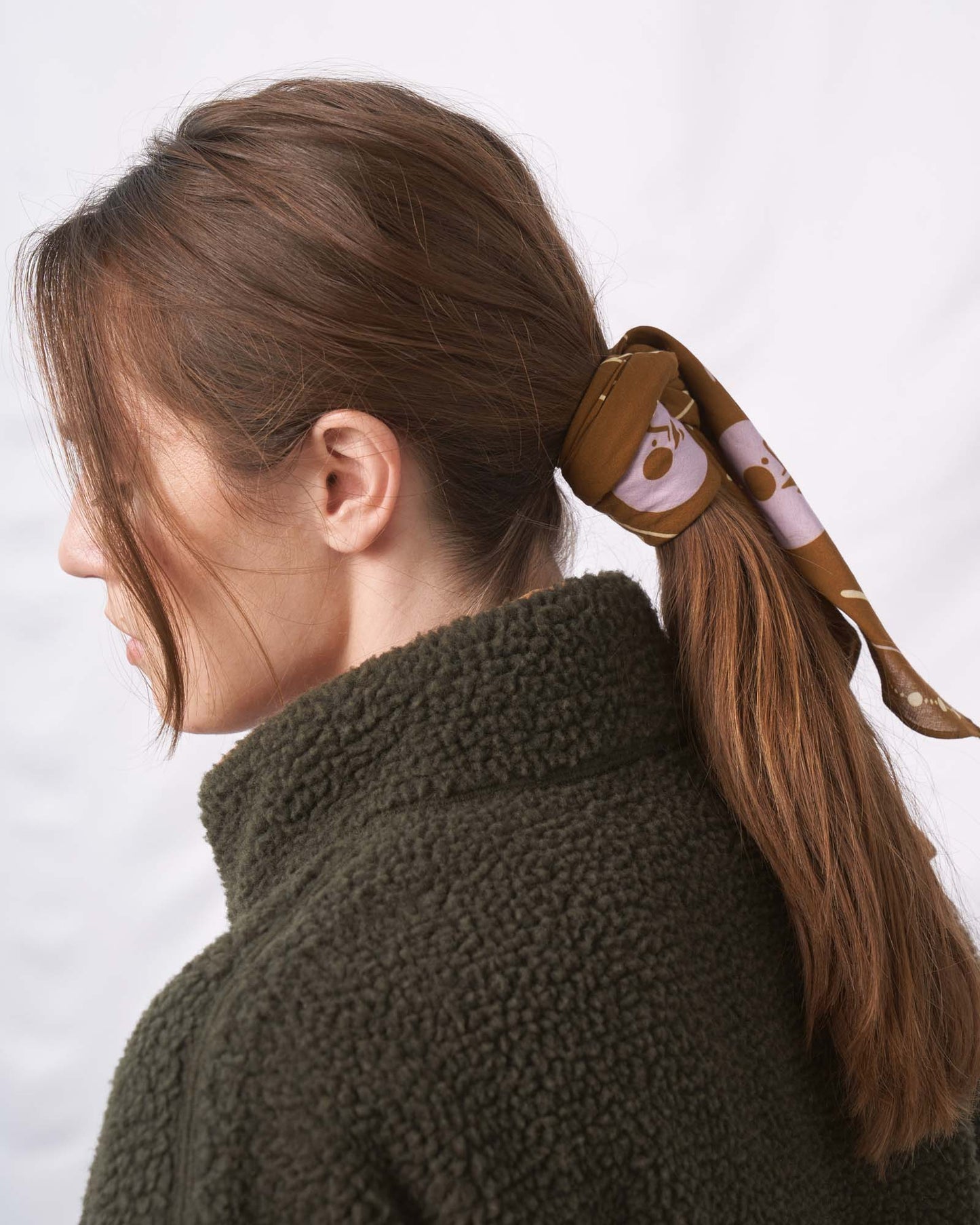 Smoky Ochre Organic Cotton Bandana from United By Blue used as hair tie on female model.
