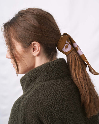 Smoky Ochre Organic Cotton Bandana from United By Blue used as hair tie on female model.