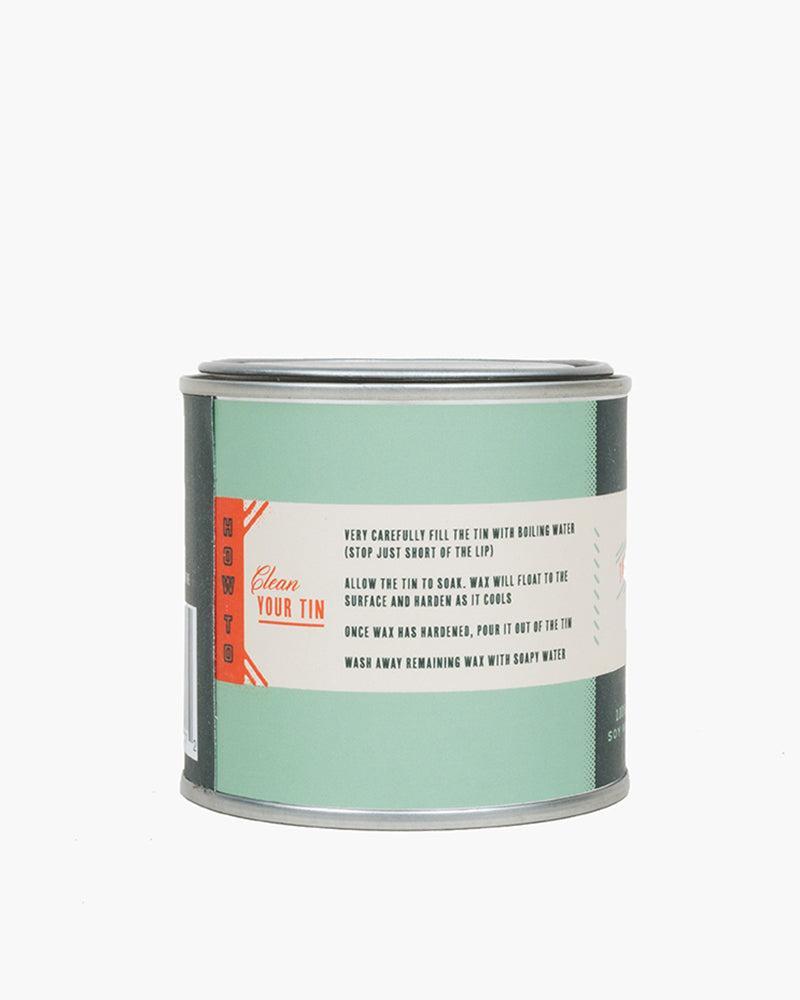 100% GMO-free soy wax for a soot-free, non-toxic burn the 5oz Scout Citronella Candle from United By Blue is displayed on a white background showing label instructions on how to clean your tin.