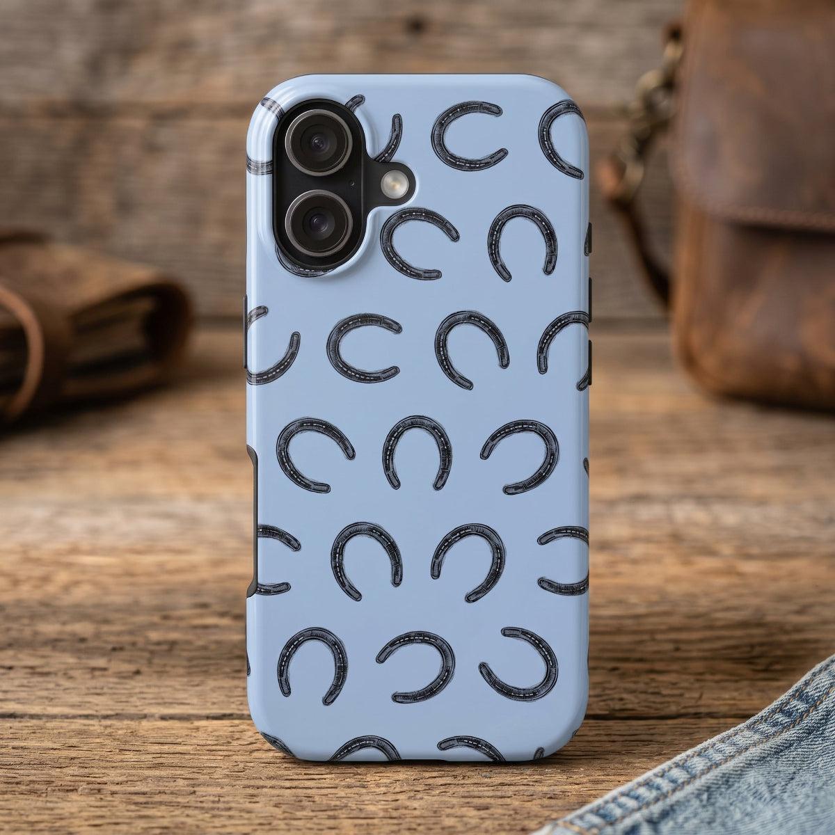 The Lucky Horseshoe Phone Case for iPhone 17 by Kempain Family Outfitters in  a rustic wooden surface.