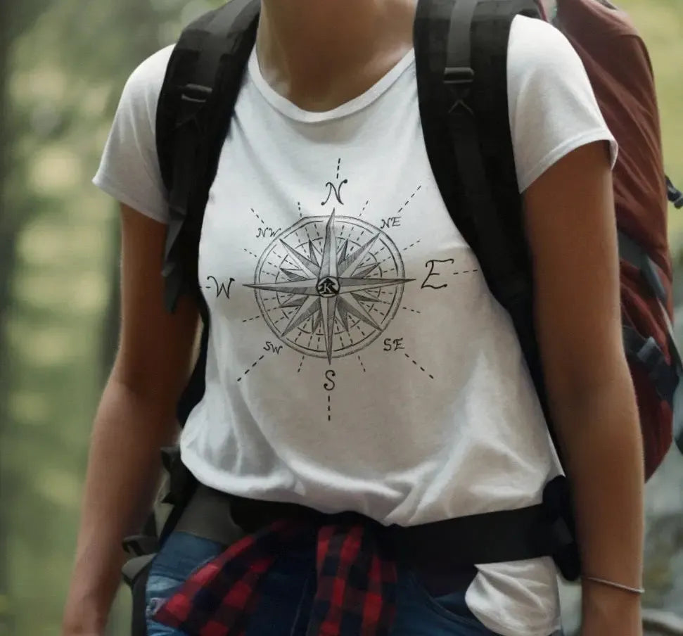 Female hiker wearing The True North Compass 100 percent cotton Unisex T-Shirt by Kempain, white, available in sizes Small through 5XL.