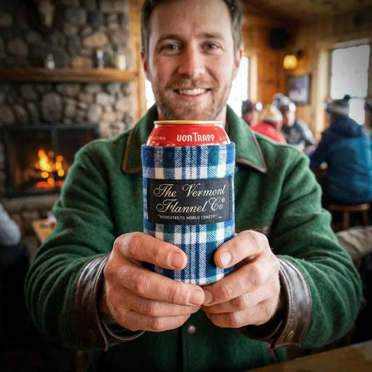 Man holding a can with 'The Vermont Flannel Co.' branding in a cozy indoor setting.
