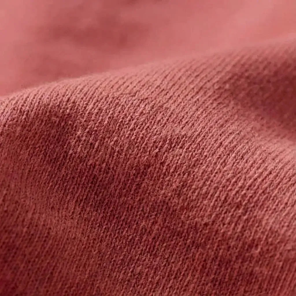 Close-up detail of the 6.4 oz Comfort Colors 1466 garment-dyed natural cotton fabric texture in a deep terracotta tone.